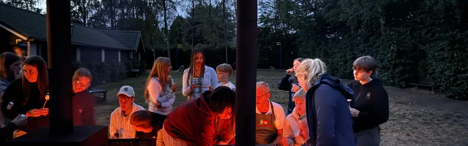 Deelnemers rond een houtkachel in de avond