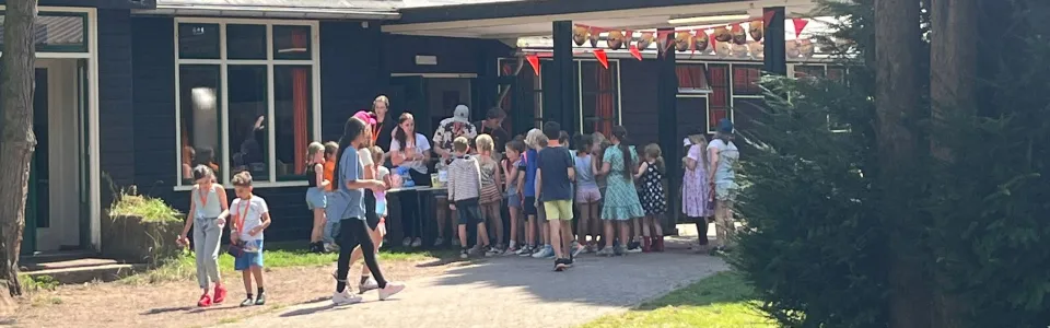 Kinderen verzamelen zich rond de uitgifte bij het kamphuis