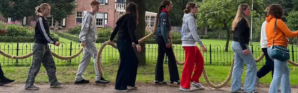 Tieners volgen samen een touw langs een groene buitenplaats