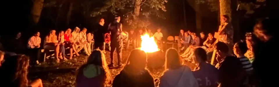 Jongeren zitten samen rond een knisperend kampvuur in het bos