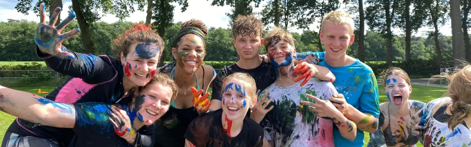 Deelnemers onder de modder poseren samen