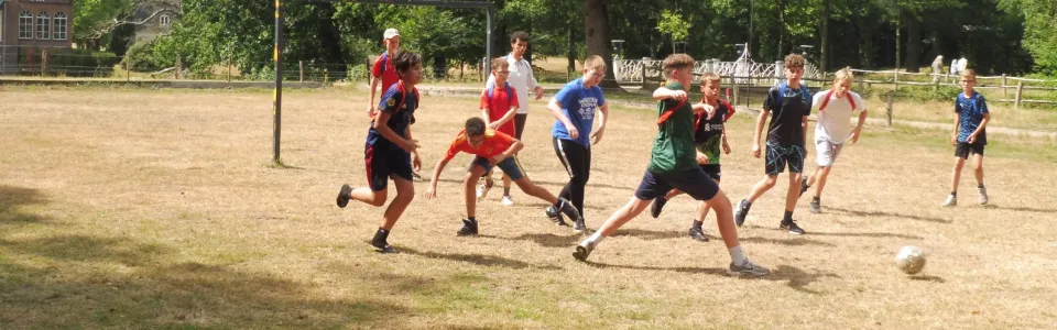 Tieners spelen enthousiast voetbal op het zonnige kampterrein