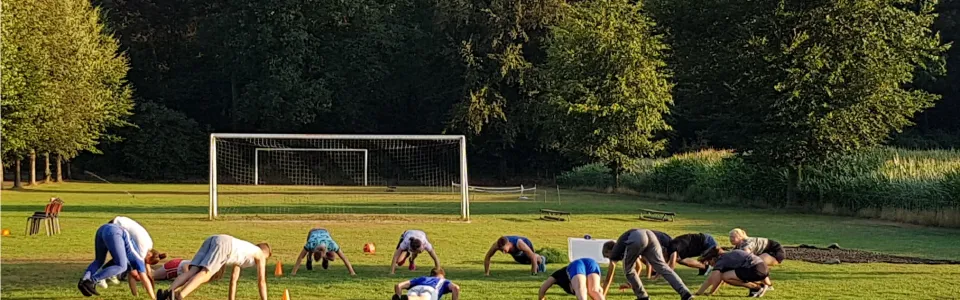 Deelnemers doen oefeningen op een sportveld