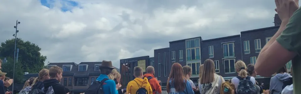 Deelnemers staan in een rij buiten met de handen omhoog