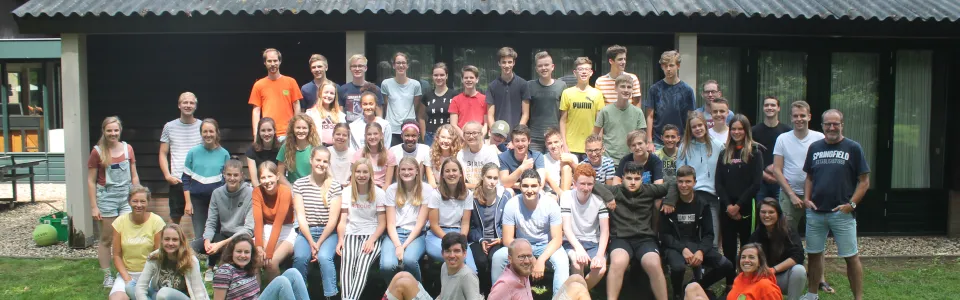 Grote groepsfoto van deelnemers voor het kampgebouw
