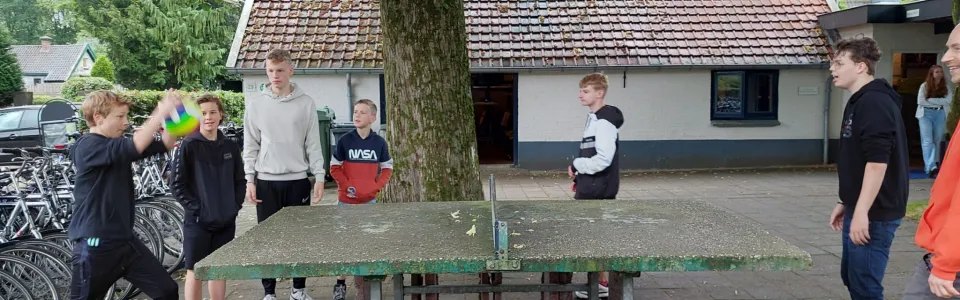 Deelnemers spelen tafeltennis bij het kampgebouw