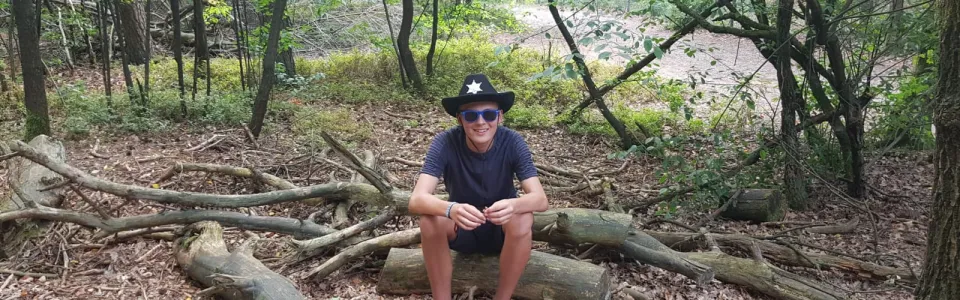 Deelnemer zit op een boomstam in het bos