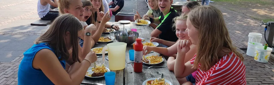 Deelnemers eten samen aan picknicktafels