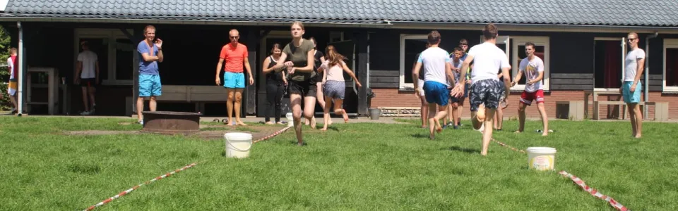 Deelnemers spelen een spel op het grasveld bij het gebouw