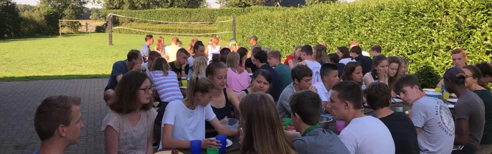 Deelnemers eten samen aan tafels buiten