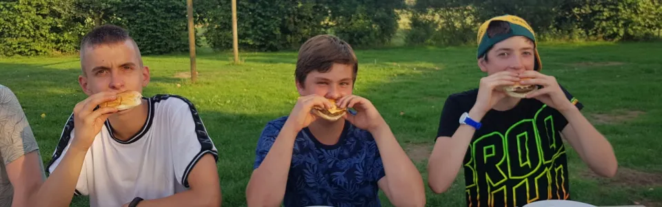 Deelnemers eten een broodje aan tafel buiten