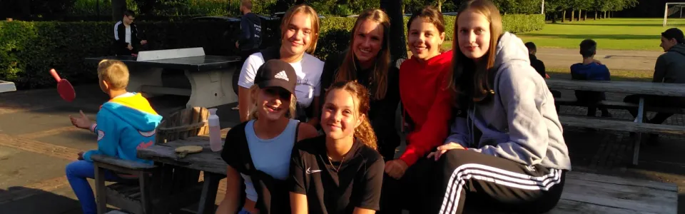 Deelnemers zitten op een picknicktafel