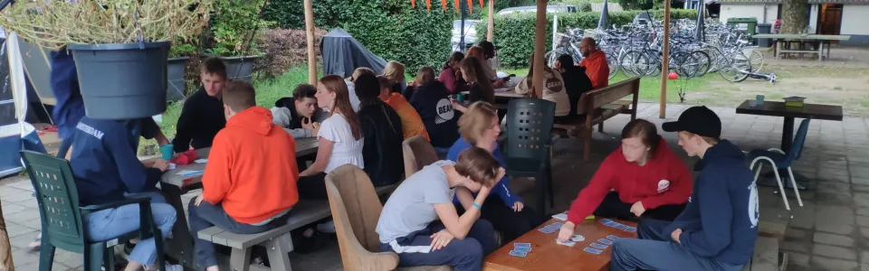 Deelnemers zitten onder een luifel op het terras