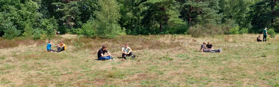 Deelnemers zitten verspreid op de heide