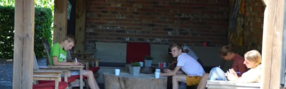 Deelnemers aan tafel onder een overkapping met vlaggetjes