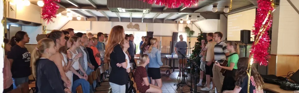 Deelnemers in een zaal met rode slingers tijdens het avondprogramma