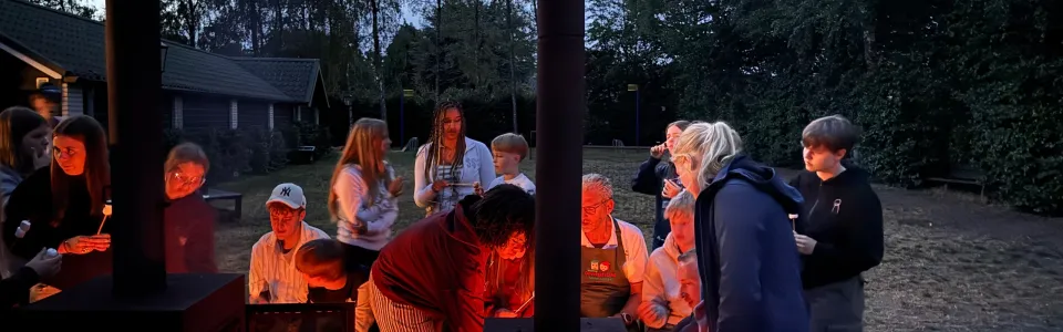 Deelnemers rond een houtkachel in de avond