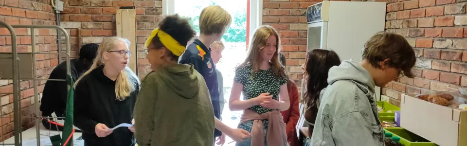 Deelnemers vullen bekers in een ruimte met bakstenen muur