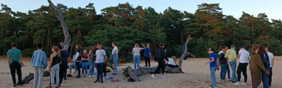 Deelnemers verzamelen zich op de zandvlakte bij avondlicht