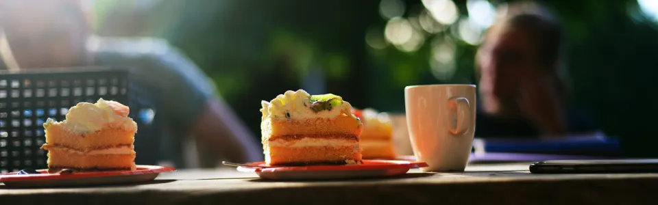 Cake en een beker op een houten tafel buiten