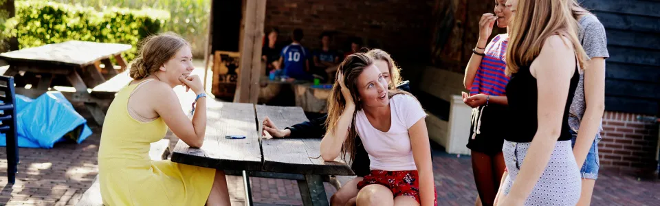 Deelnemers zitten op picknicktafels onder een afdak