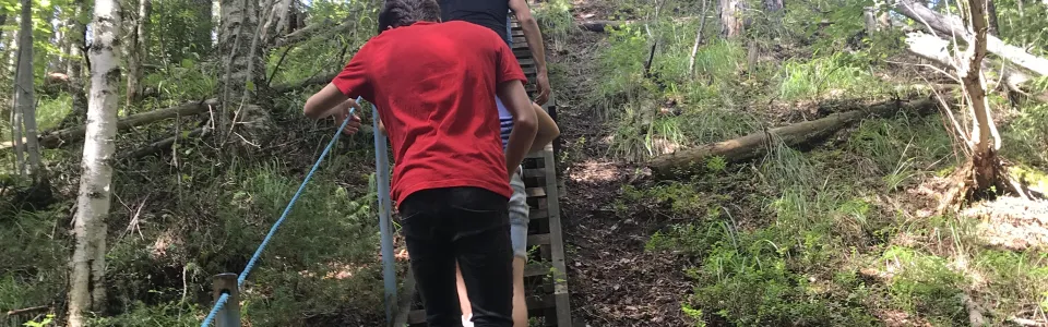 Deelnemer loopt een houten trap op in het bos