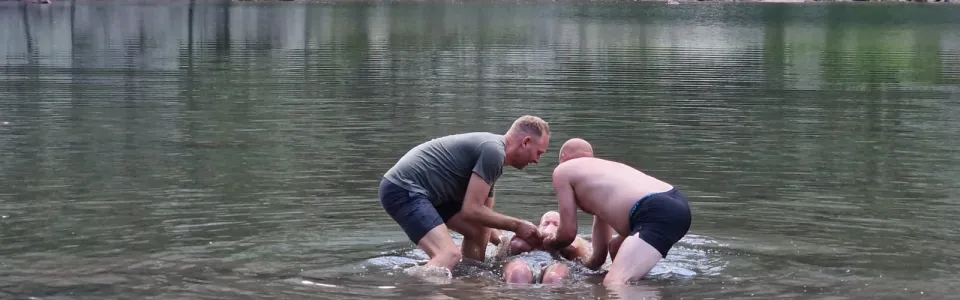 Doop van een deelnemer in het water van een bergmeer