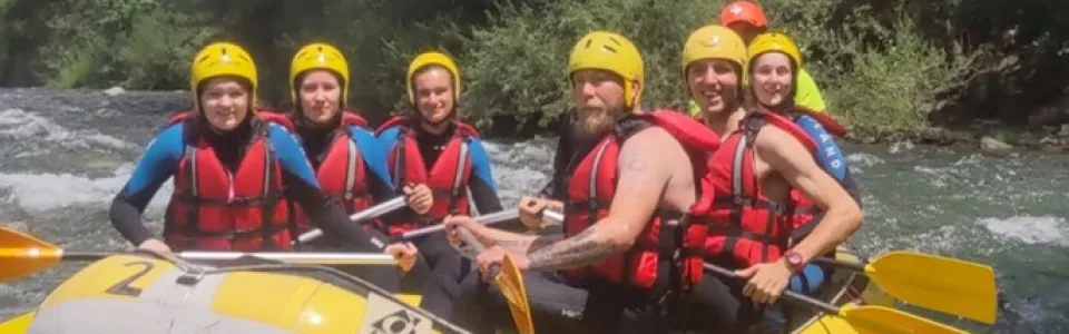 Deelnemers met helm en zwemvest in een raft