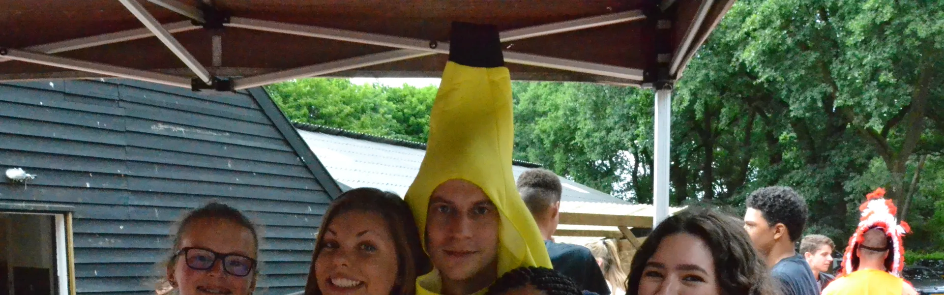 Deelnemers verkleed als banaan poseren bij het kampgebouw