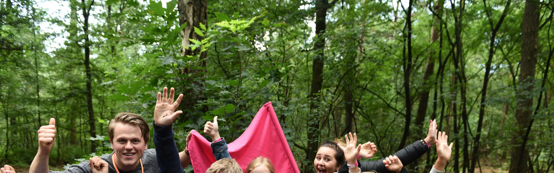 Kampleider en kinderen juichen in het bos