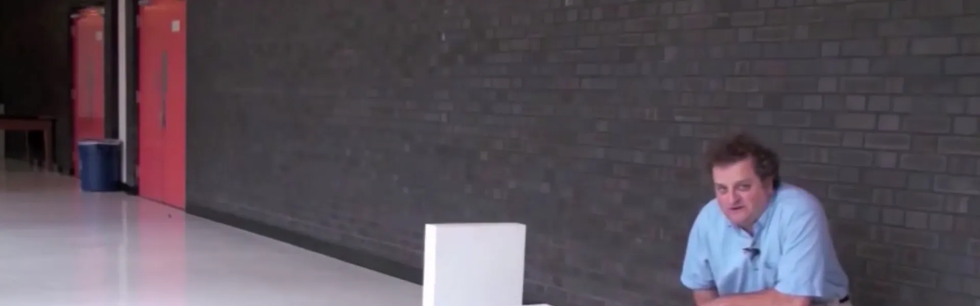 Spreker bij een rij dominostenen tijdens een presentatie