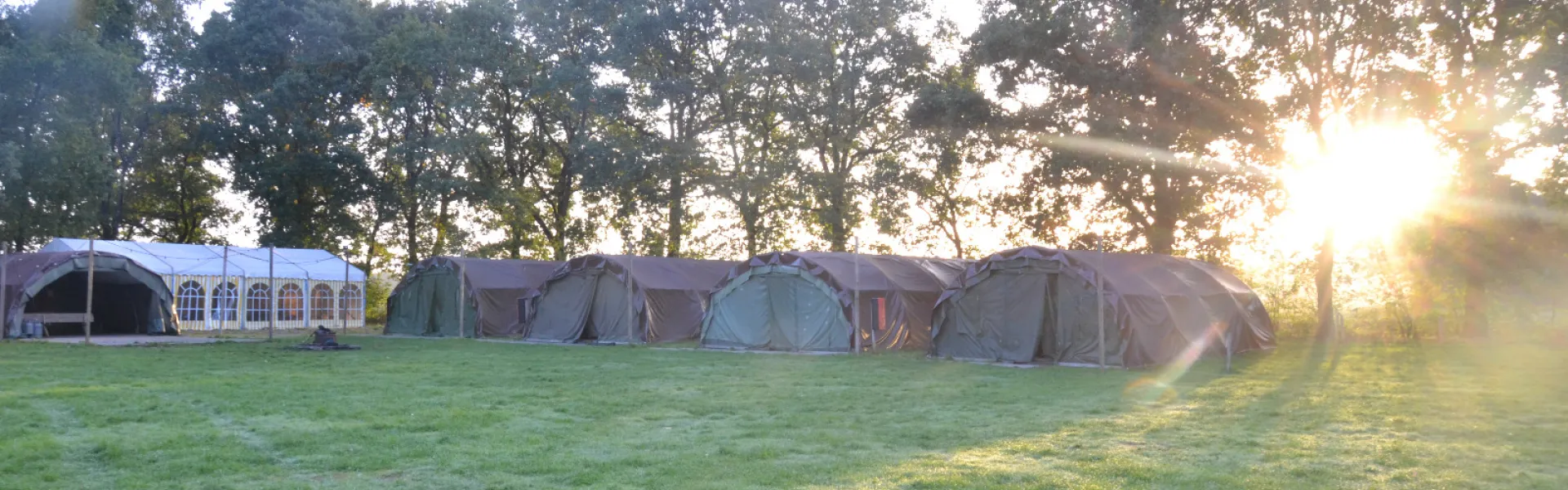 Rij tenten op een grasveld bij zonsopgang