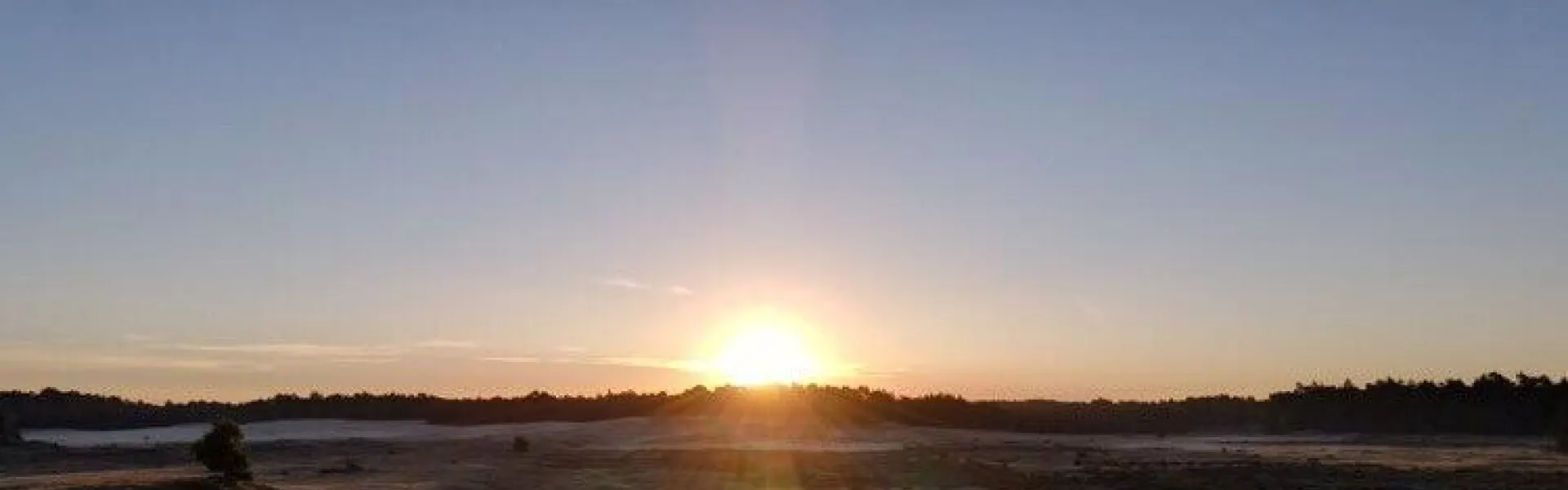 Zonsondergang boven de zandvlakte met deelnemers