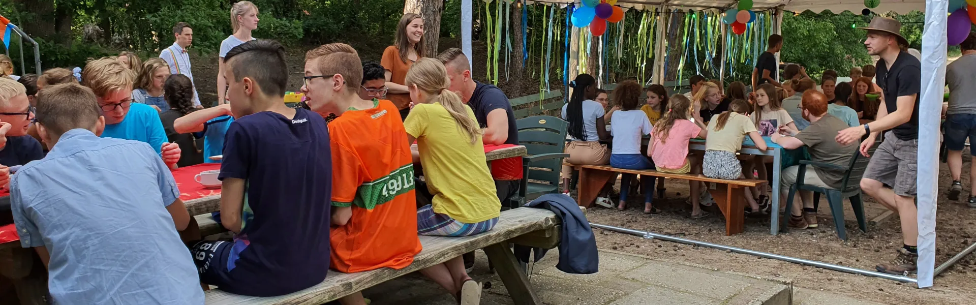 Deelnemers aan picknicktafels onder een partytent