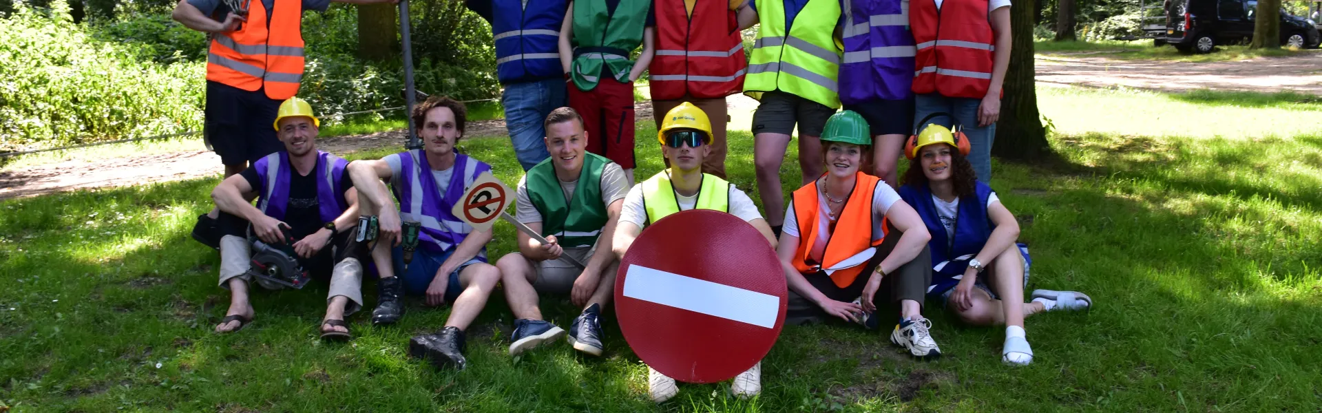 Deelnemers in veiligheidshesjes poseren met verkeersborden