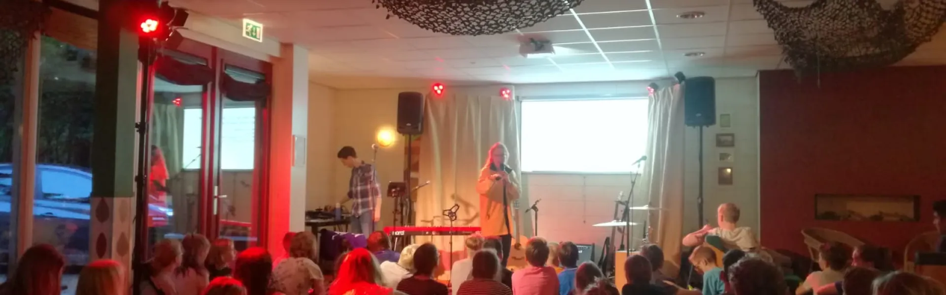 Volle zaal in rood licht tijdens het programma