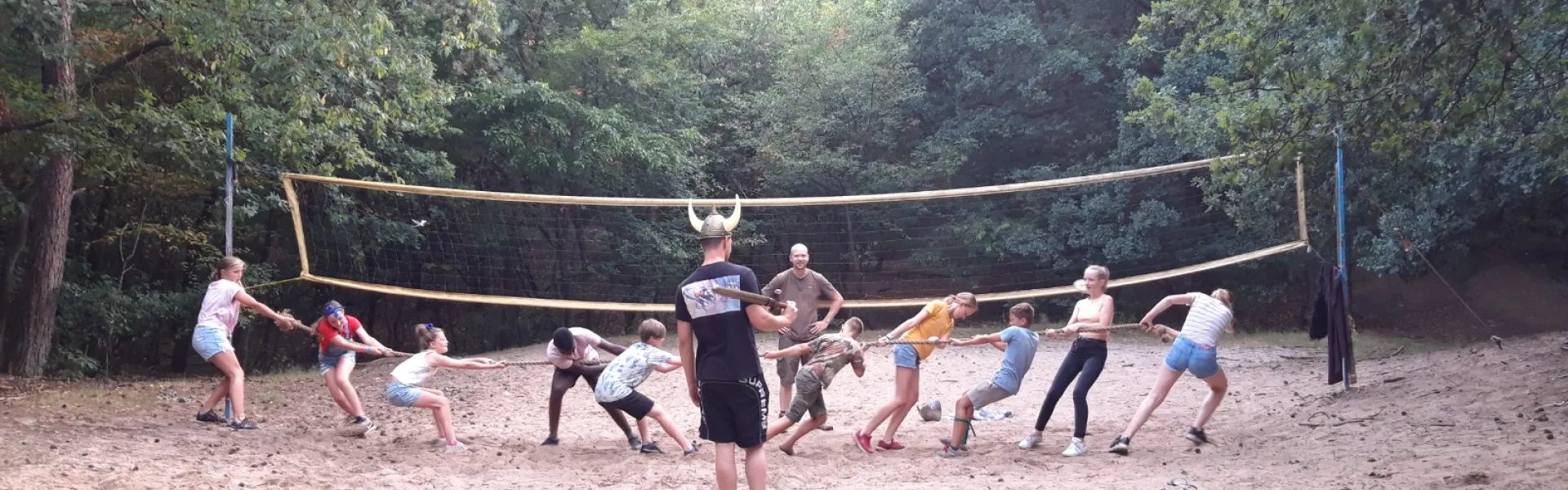 Deelnemers spelen volleybal op het zandveld