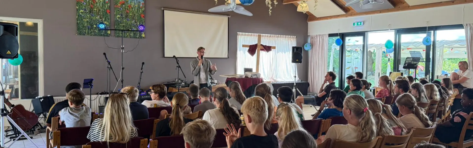 Volle zaal met deelnemers onder papieren slingers