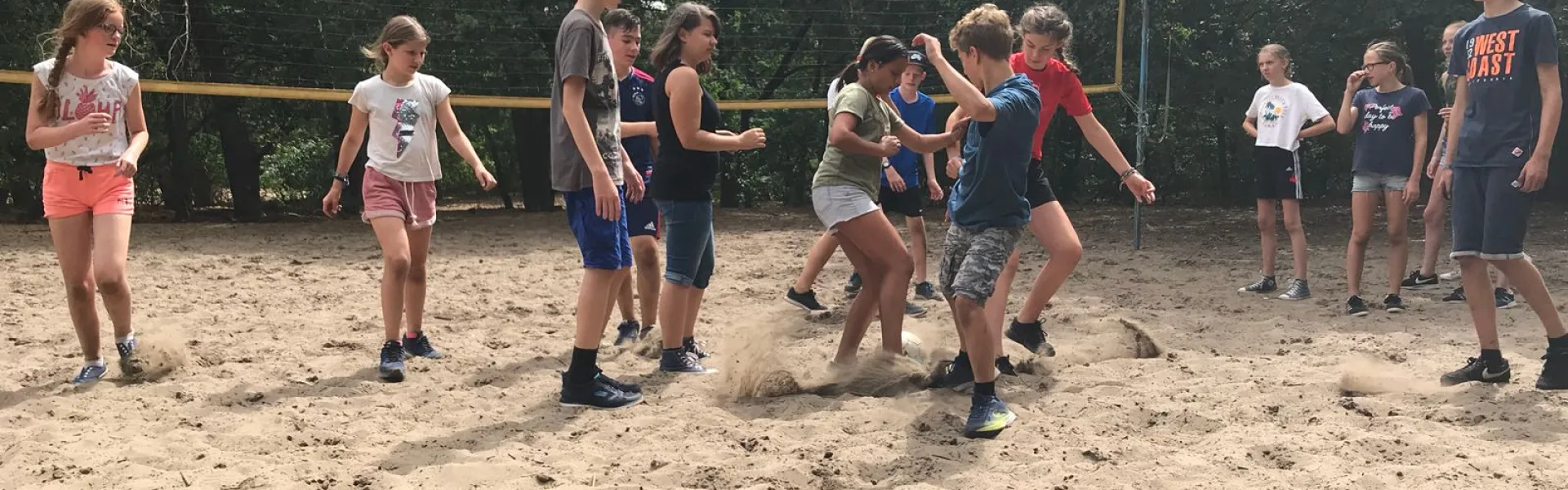 Deelnemers spelen volleybal op het zandveld
