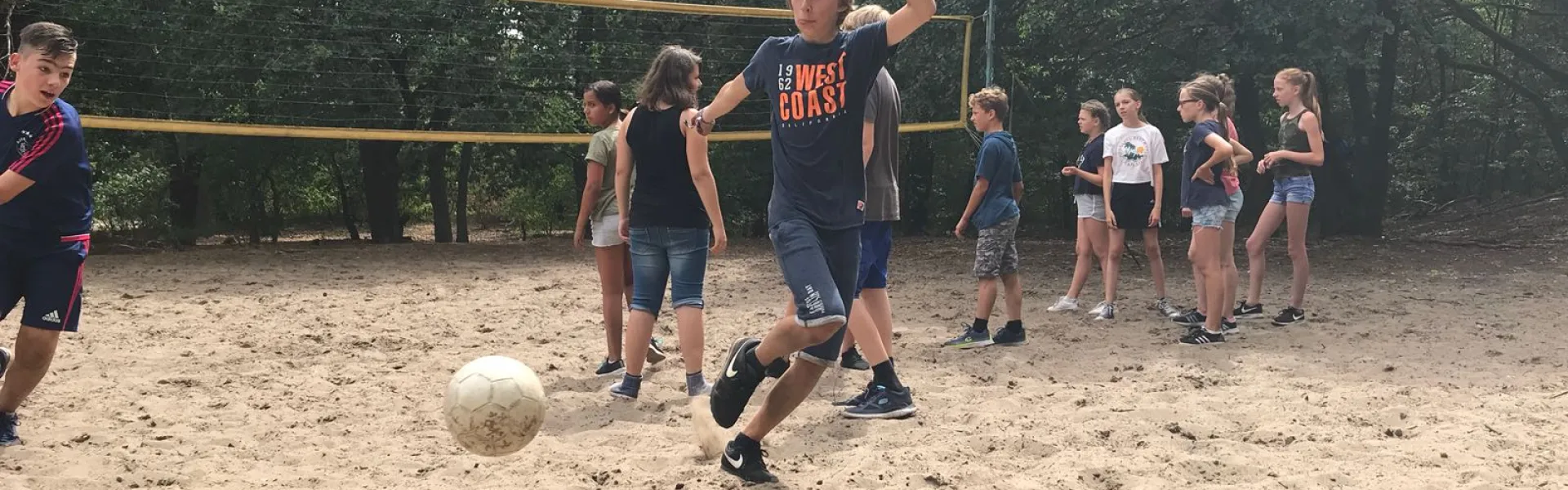Deelnemers spelen volleybal met publiek eromheen