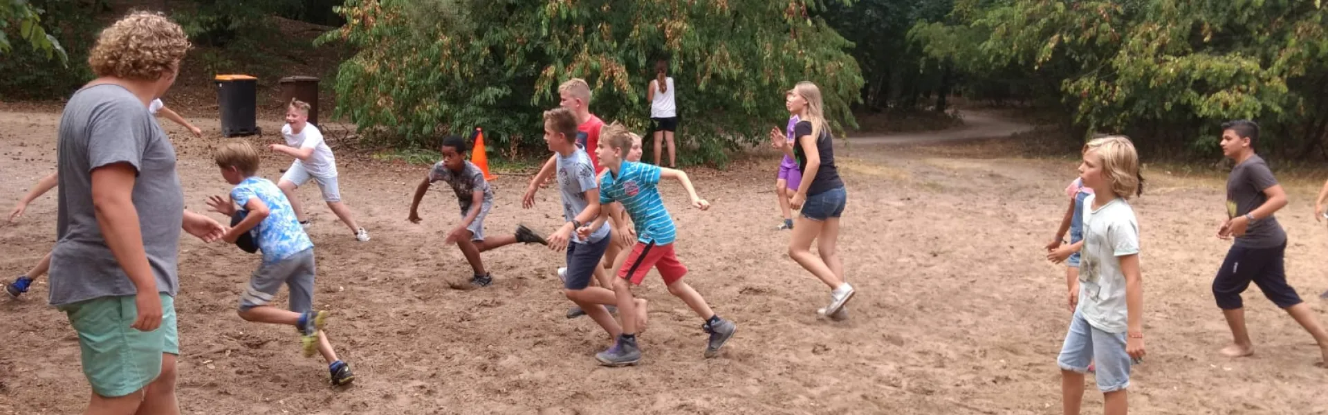 Deelnemers rennen over het zandveld tijdens een spel
