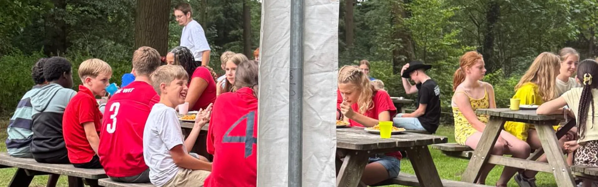 Deelnemers bij picknicktafels onder een parasol
