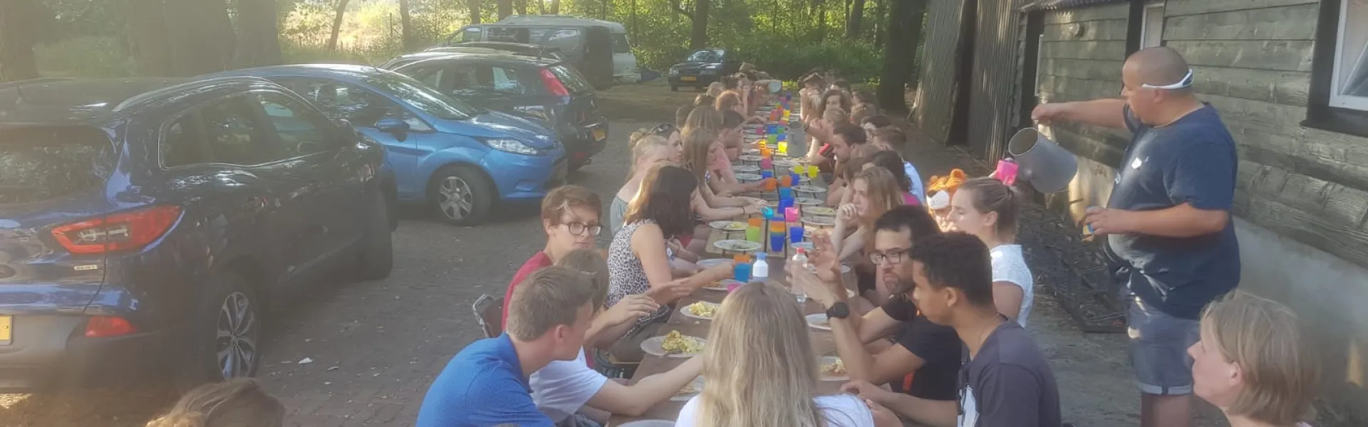 Deelnemers eten aan lange tafels buiten