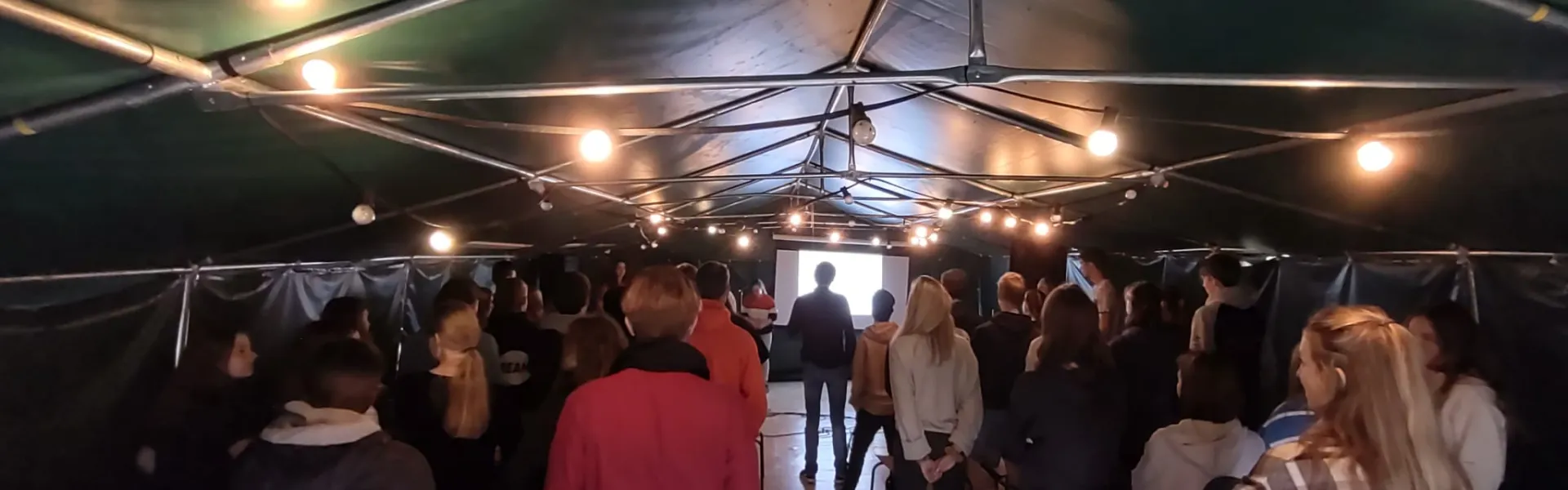 Deelnemers lopen door de partytent tijdens het programma