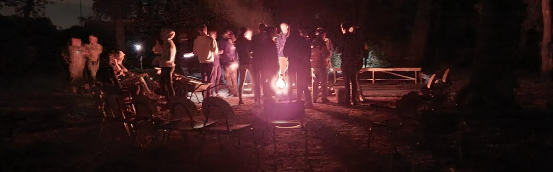 Kampvuur in het donker met deelnemers eromheen
