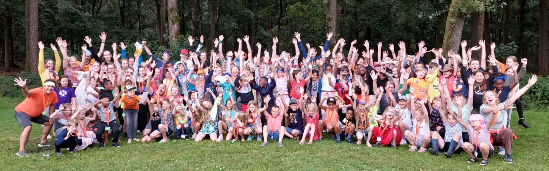 Grote groepsfoto van deelnemers met de handen omhoog