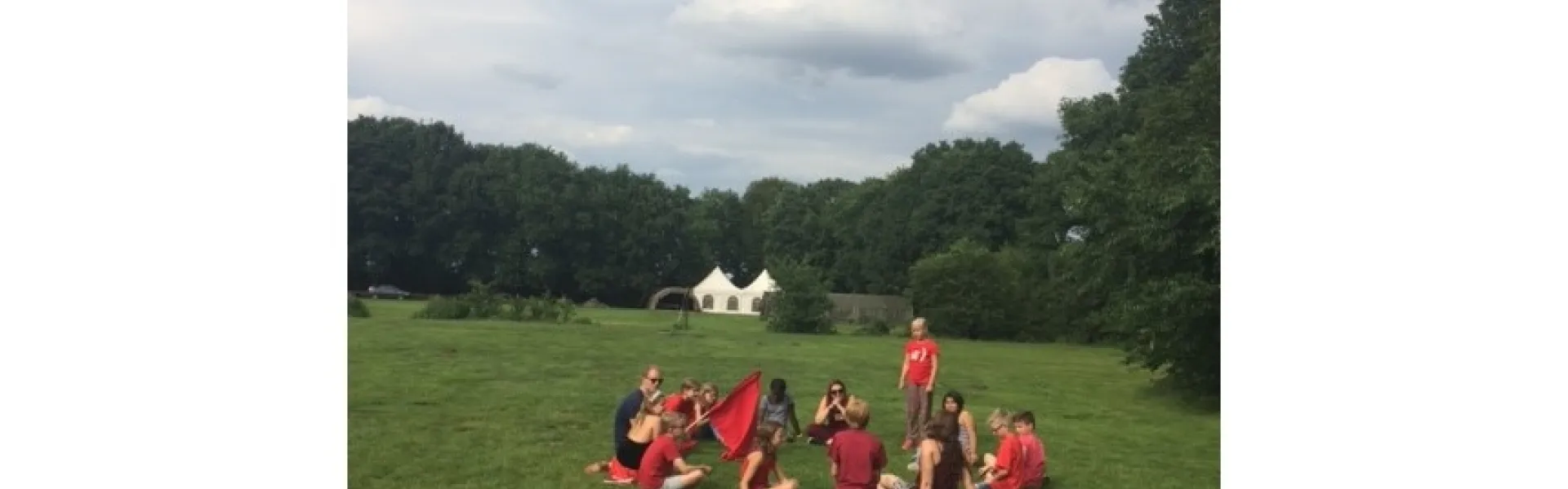 Deelnemers zitten in een kring op een grasveld