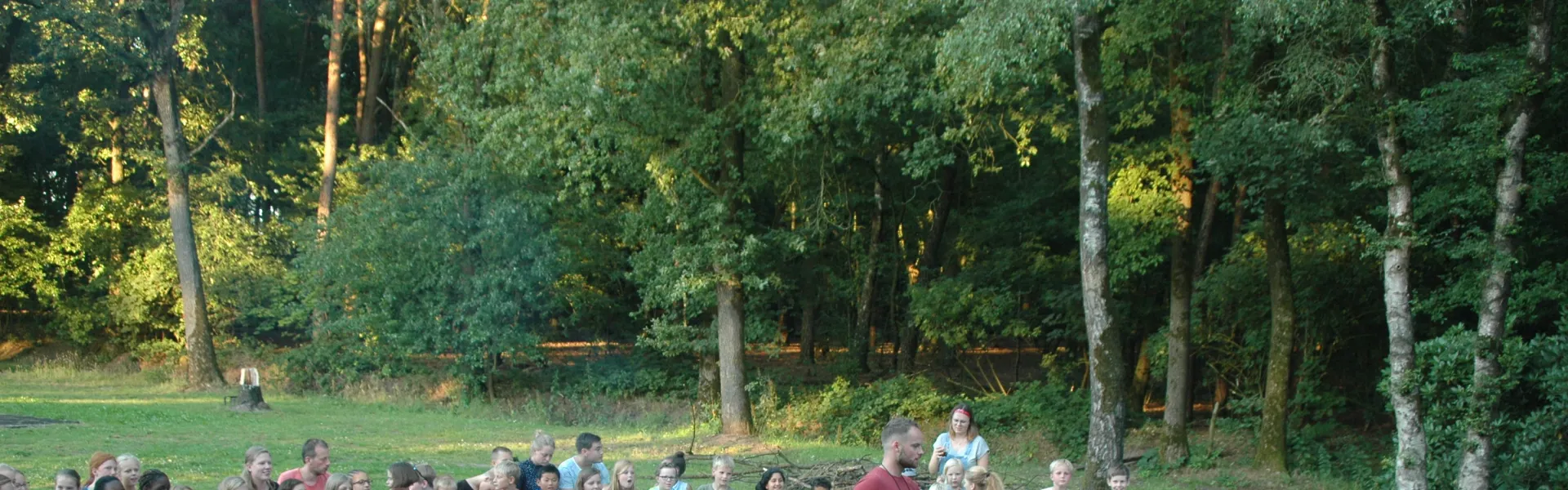 Deelnemers zitten op stoelen buiten tijdens het programma