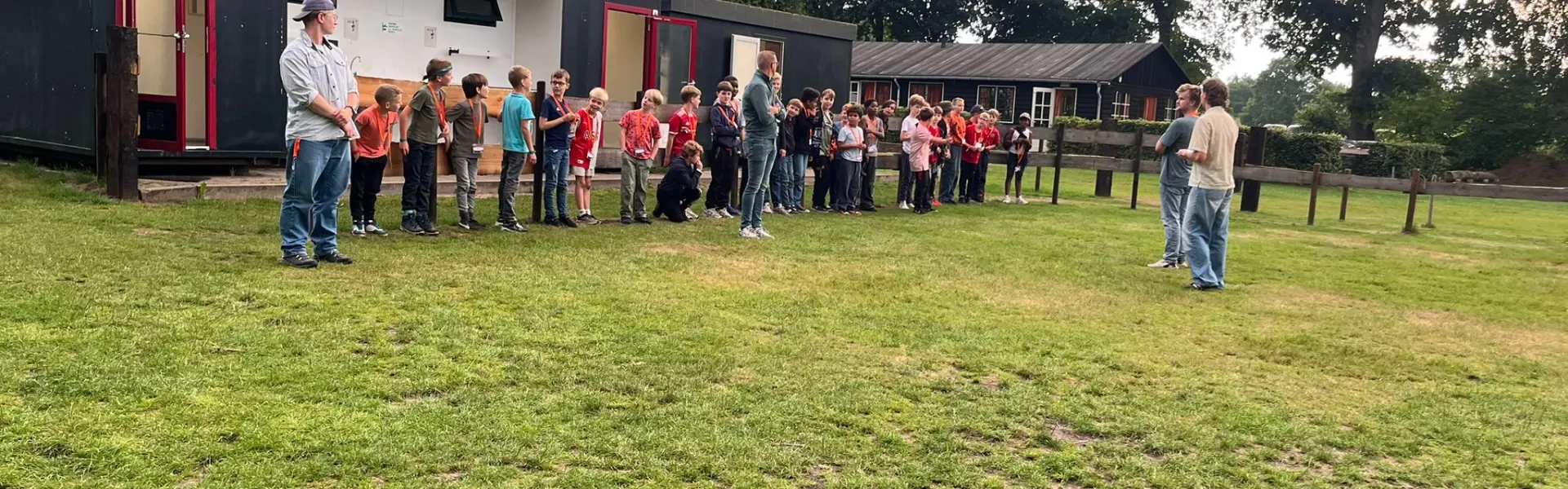 Deelnemers verzamelen zich op het grasveld bij het gebouw