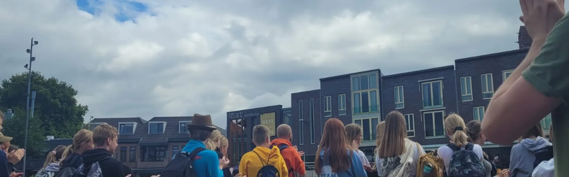 Deelnemers staan in een rij buiten met de handen omhoog